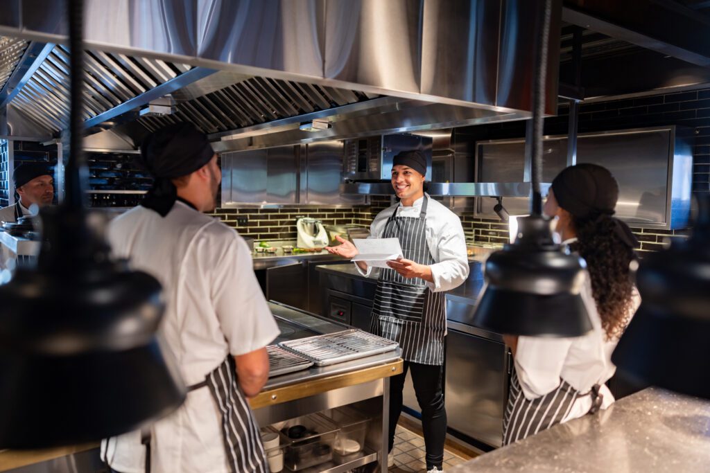 Chef explaining the menu to a group of cooks at a restaurant