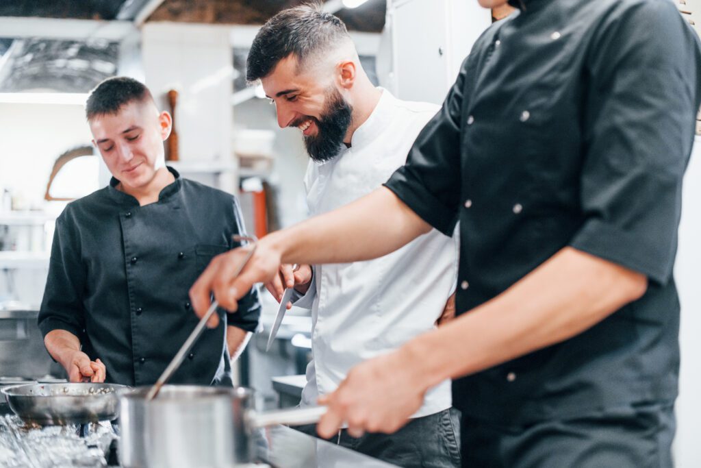 Group of people cooking food at kitchen together. Busy day at work